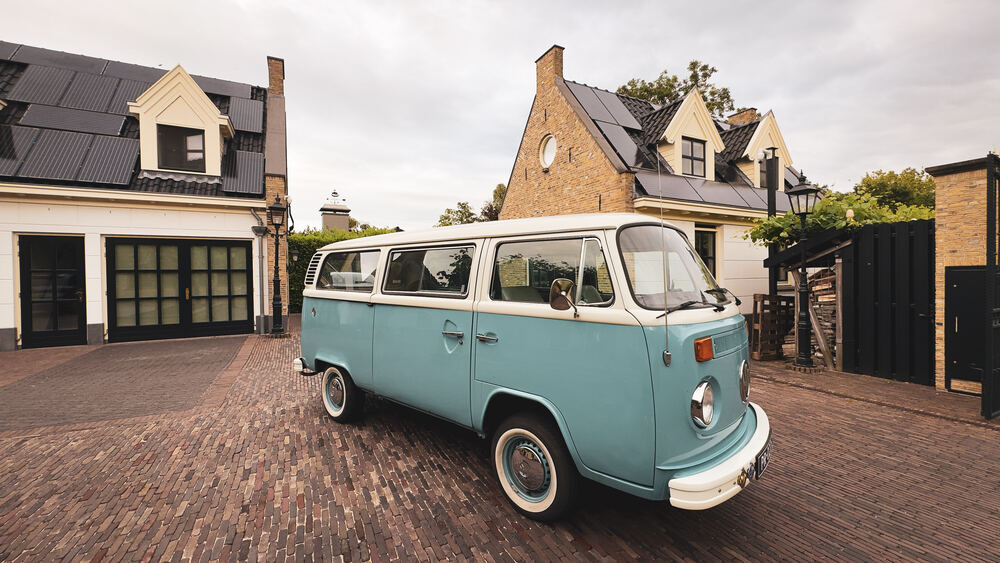 De zeegroene bus van de zijkant op de oprit voor het huis.